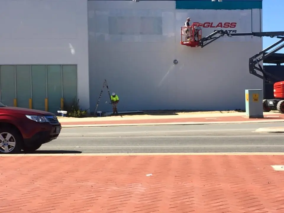 Boom lift against a commercial facade mid-repaint