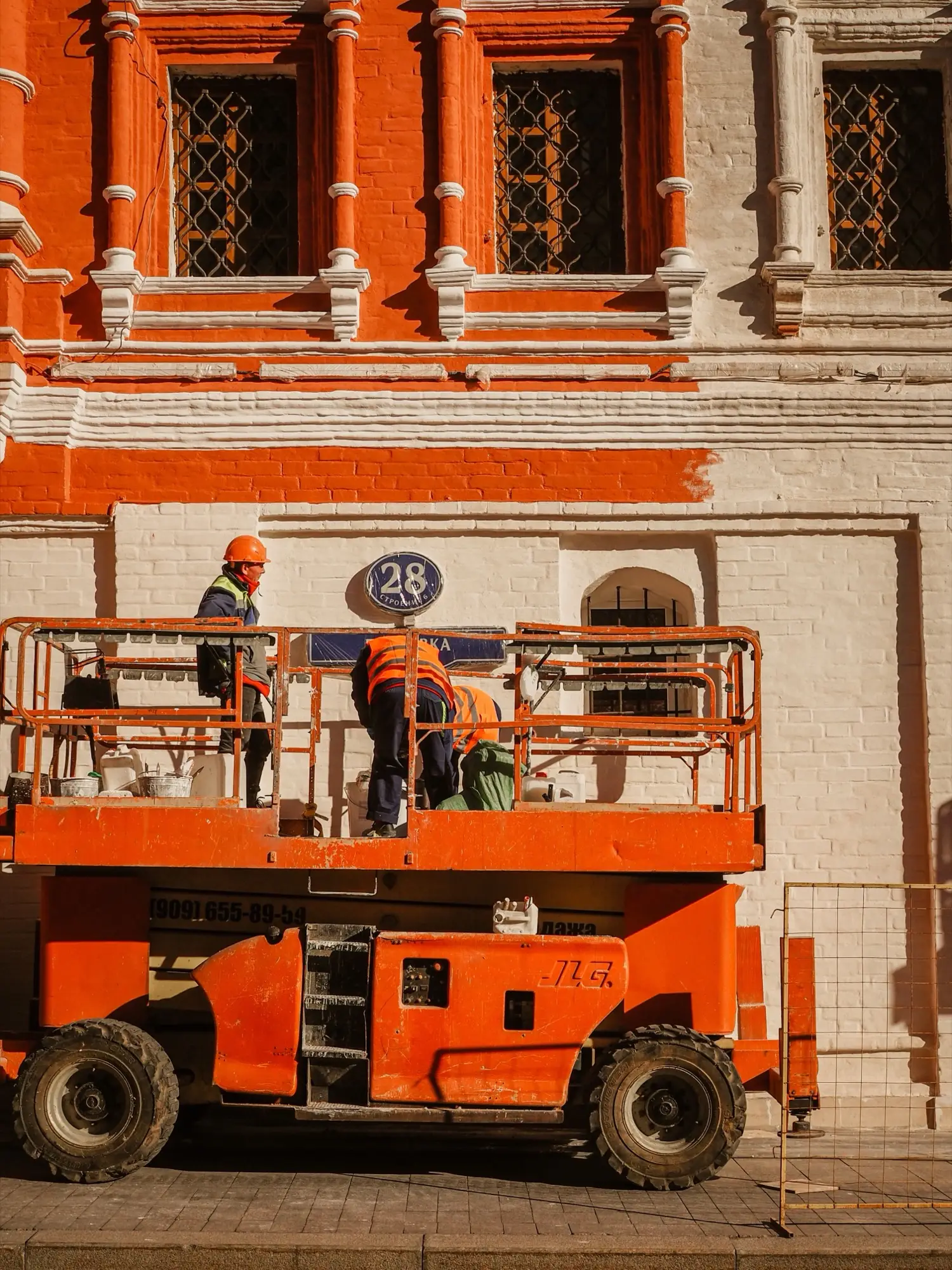 Painters working from an elevated platform painting a building exterior