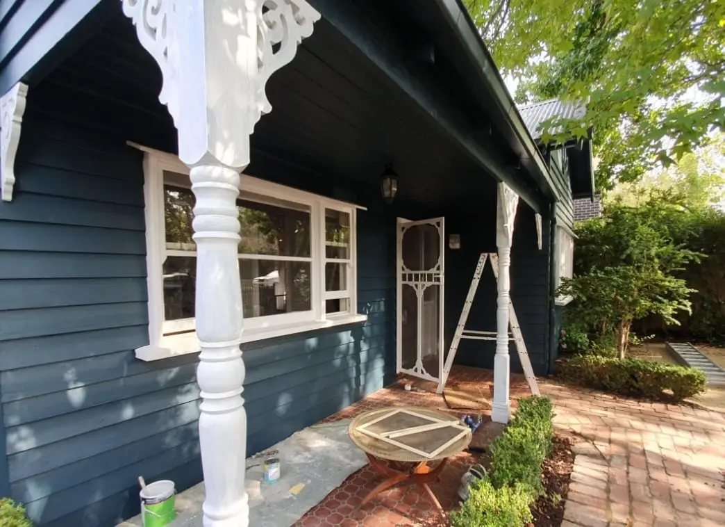 Weatherboard cottage verandah repainted in deep blue-green, fretwork, posts and window trim picked out in white